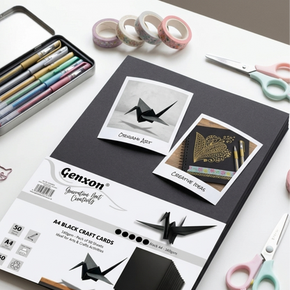 Black craft cards with origami designs on a white surface with stationery items.
