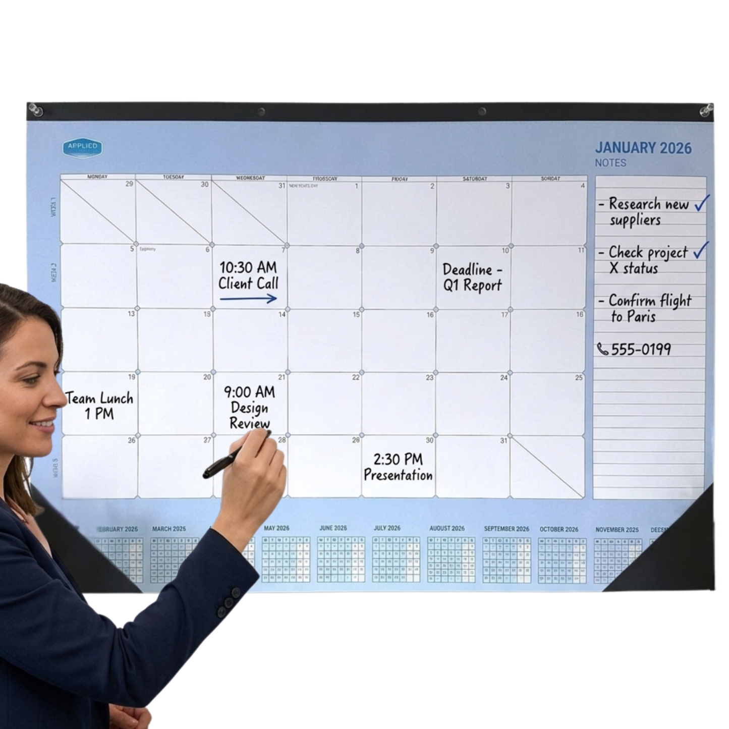 Woman writing on a large wall calendar with a pen, showing a schedule for January 2026.
