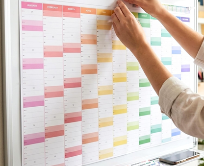 Person interacting with a colorful calendar on a wall