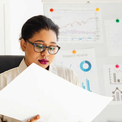 Woman holding A2 card sheet with financial charts in the background