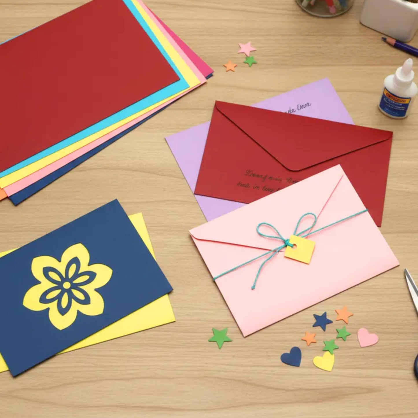 Colorful paper cards and envelopes on a wooden surface with decorative items.
