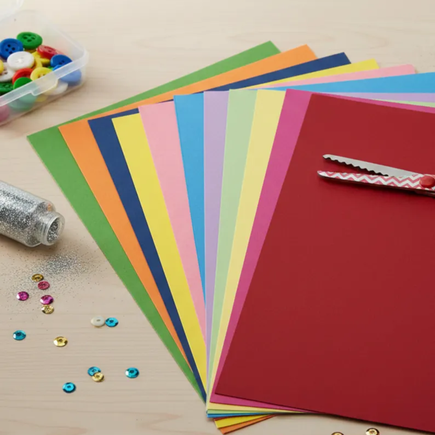 Colorful paper sheets and craft supplies on a wooden surface