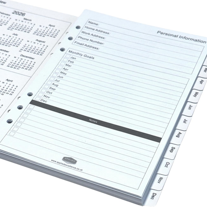 A close-up of a white ring-binder planner or agenda showing the personal information page with fields for name, home address, work address, phone number, email address, monthly goals, and notes. Tabbed pages for months are visible along the right edge, and part of another page with calendar months appears in the background.