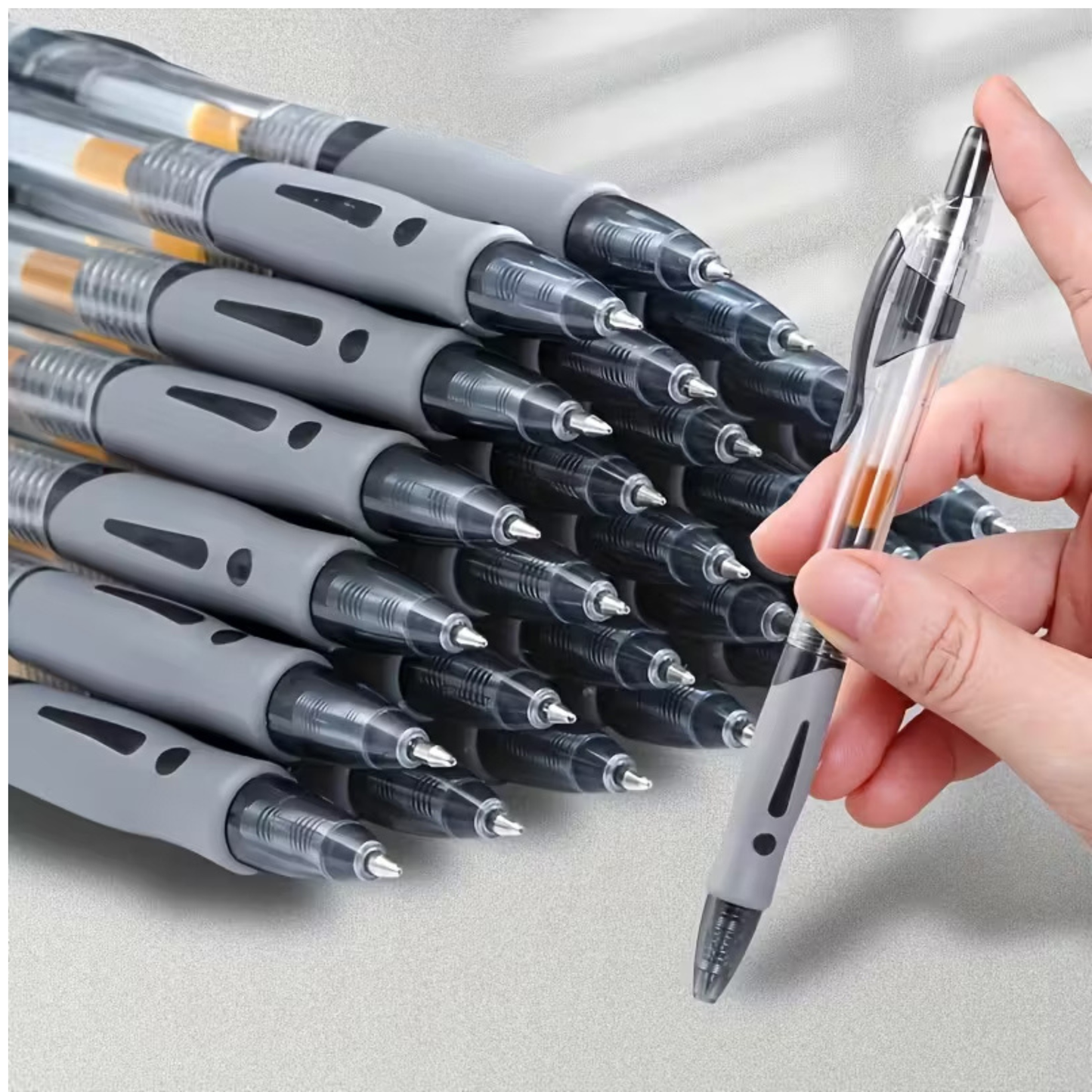 Stack of pens with a hand holding a pen on a light gray background