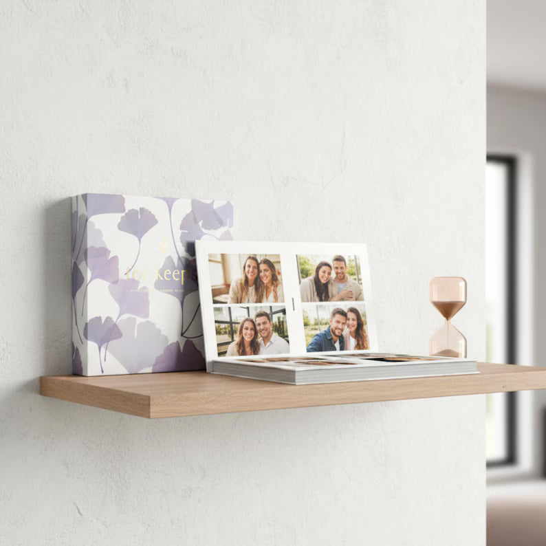 Decorative photo album with floral design on a shelf against a white wall.