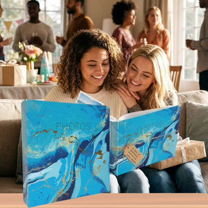 Two women looking at a photo album together in a room with people in the background.