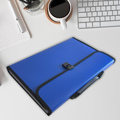 A blue textured tablet sleeve with black trim and a black elastic closure strap, shown on a white desk with a keyboard, notebook, and coffee cup nearby.