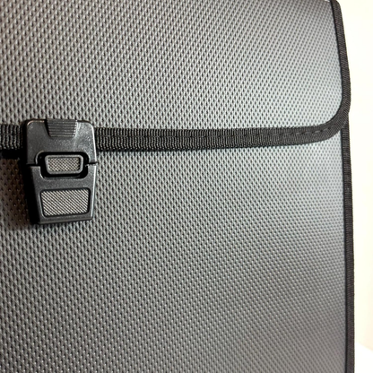 Close-up of a gray textured fabric bag with a black zipper closure and black plastic latch.