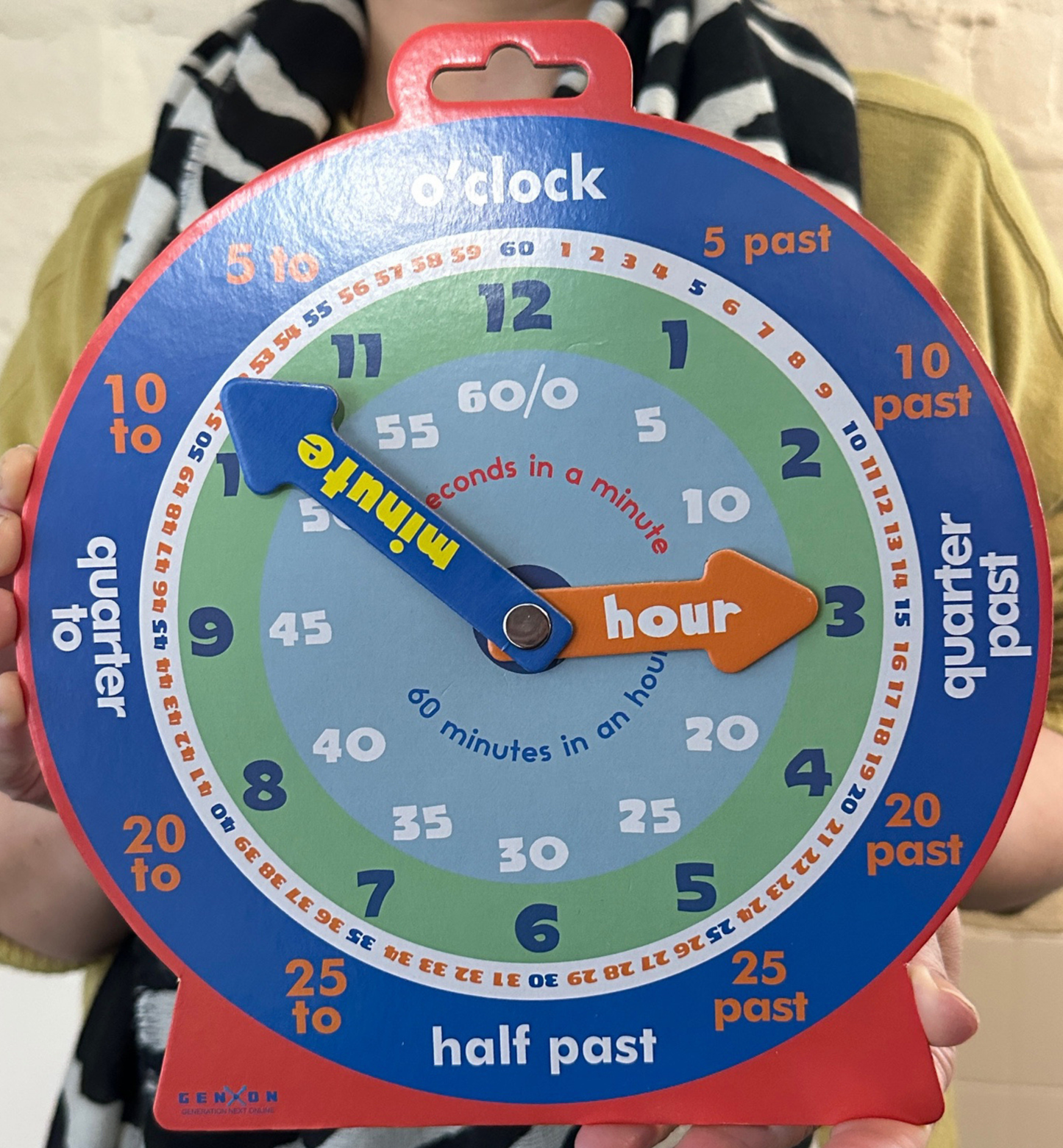 Colorful clock toy with time learning features held by a person