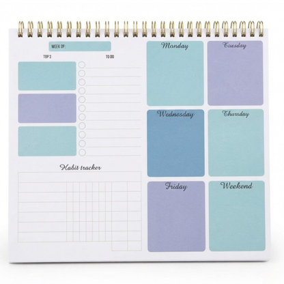 A spiral-bound planner or desk organizer shown open, with pastel weekly sections labeled Monday through Weekend and lined habit tracker areas on a white page.